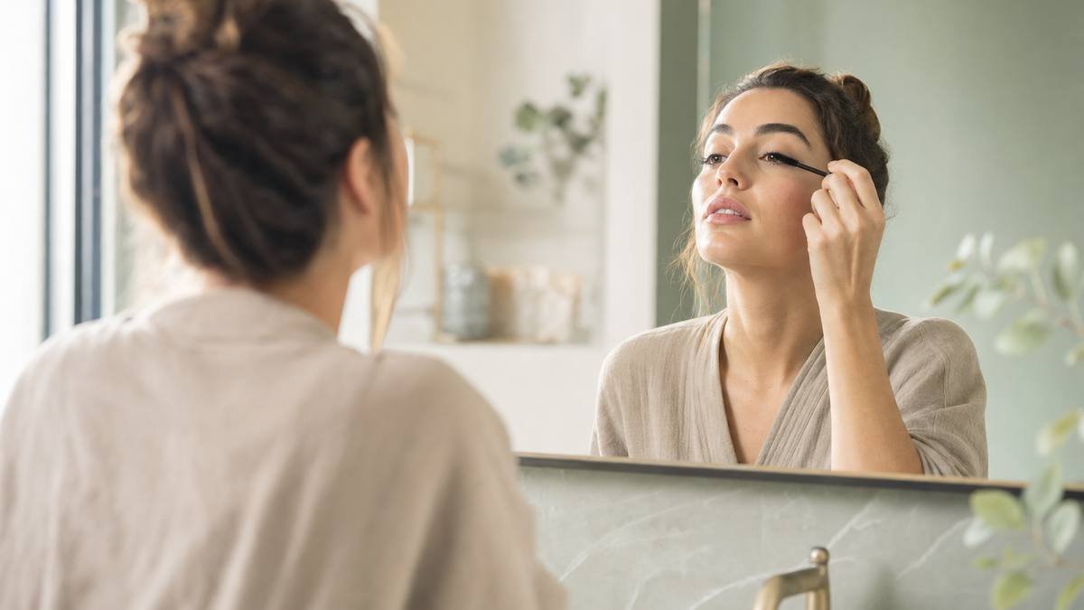 Application délicate du mascara devant un miroir